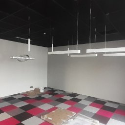 EL- BAR Bartosz Ostrowski - Wnętrze biurowe z zamontowanym oświetleniem: podwieszany sufit, szachownica na podłodze i kilka rodzajów lamp