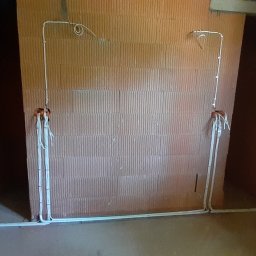 EL- BAR Bartosz Ostrowski - Surowy mur z instalacją elektryczną w trakcie montażu, widoczne kable wystające ze ścian i prowadzone wzdłuż podłogi, brak wykończenia wnętrza.