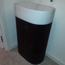 Nowoczesna umywalka wolnostojąca z czarną, żłobkowaną podstawą i białą misą, zamontowana w łazience w Ostre.