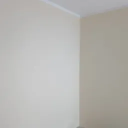 Świeżo pomalowane wnętrze pokoju w odcieniach beżu z białą listwą sufitową, widoczny fragment podłogi z panelami i listwa przypodłogowa, gniazdko elektryczne na ścianie.