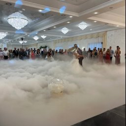 Myjnia parowa Legnica Wojciech Jurkiewicz - Pierwszy taniec pary młodej w dymie na weselu, goście w tle, kryształowe żyrandole. Romantyczna atmosfera, dekoracje sali weselnej.