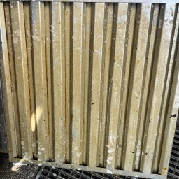 Myjnia parowa Legnica Wojciech Jurkiewicz - Brudny, żebrowany filtr przemysłowy z widocznymi śladami tłuszczu i resztkami detergentu, leżący na metalowej kracie ściekowej.