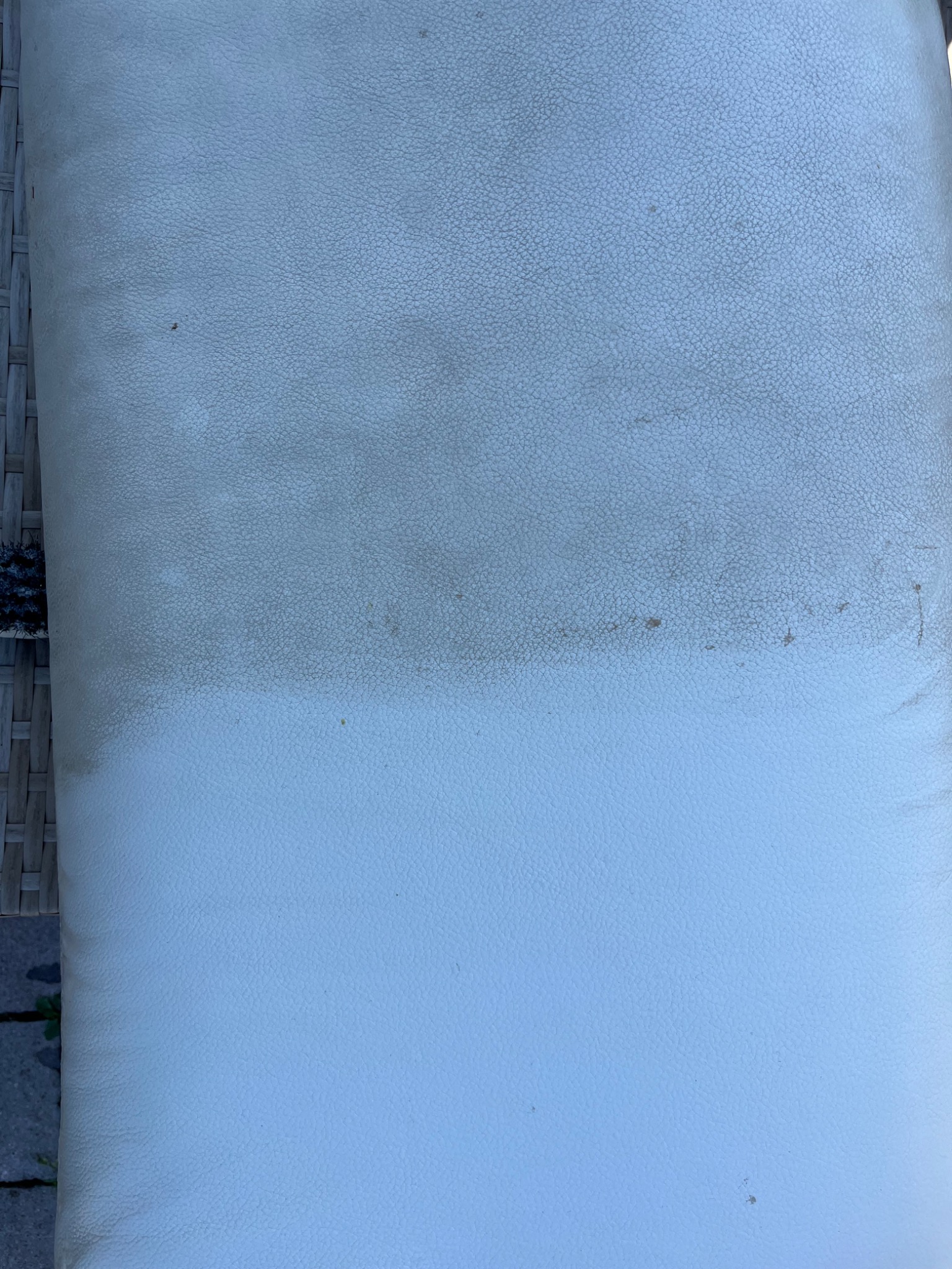 Jasny, skórzany mebel tapicerowany, częściowo wyczyszczony, z widoczną różnicą w odcieniu między czystą a zabrudzoną powierzchnią.