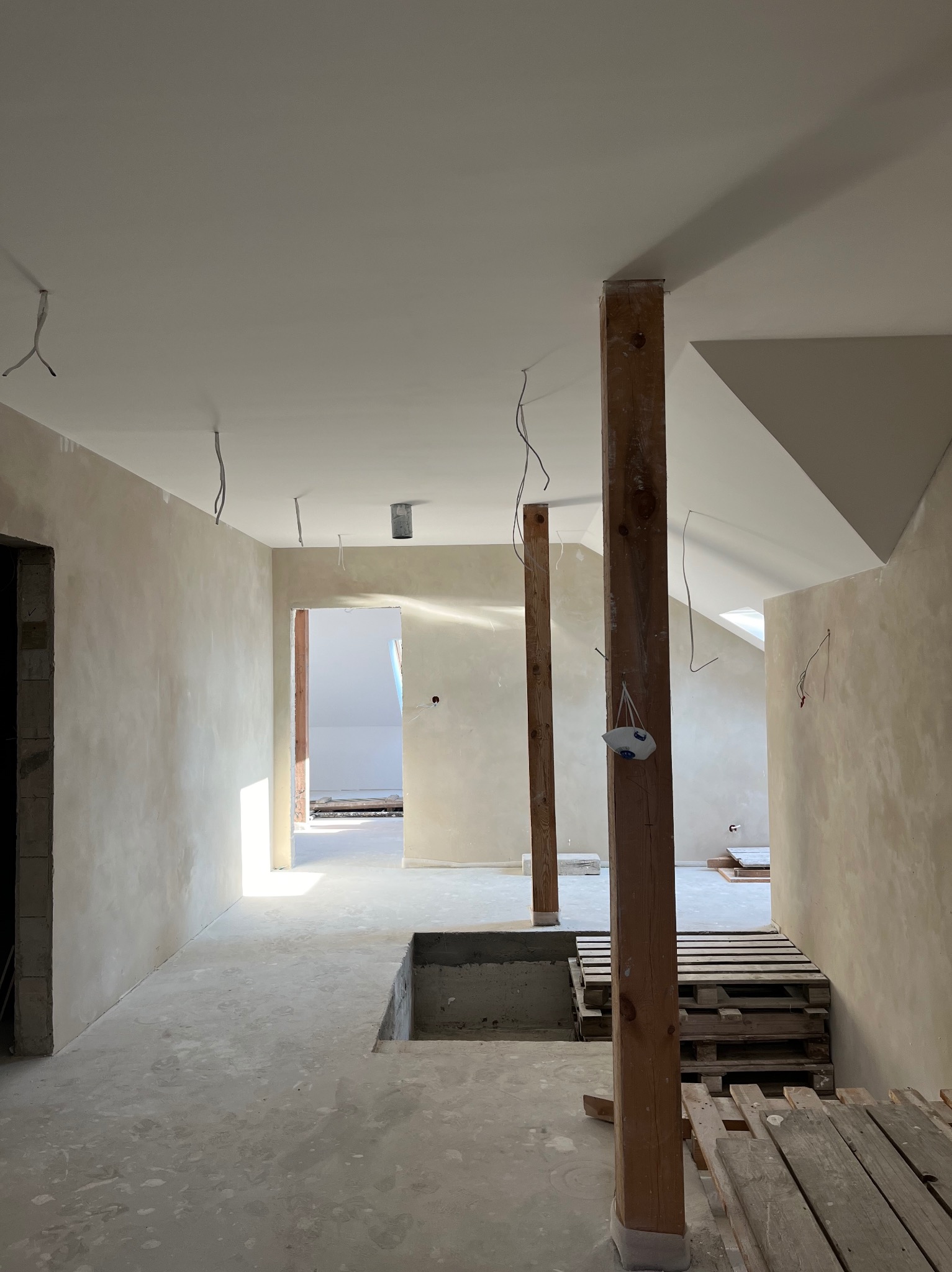 Wnętrze w trakcie prac w Ciechanowie: ściany po gładziowaniu, widoczne drewniane podpory i instalacje elektryczne. Przygotowanie do dalszych prac wykończeniowych.