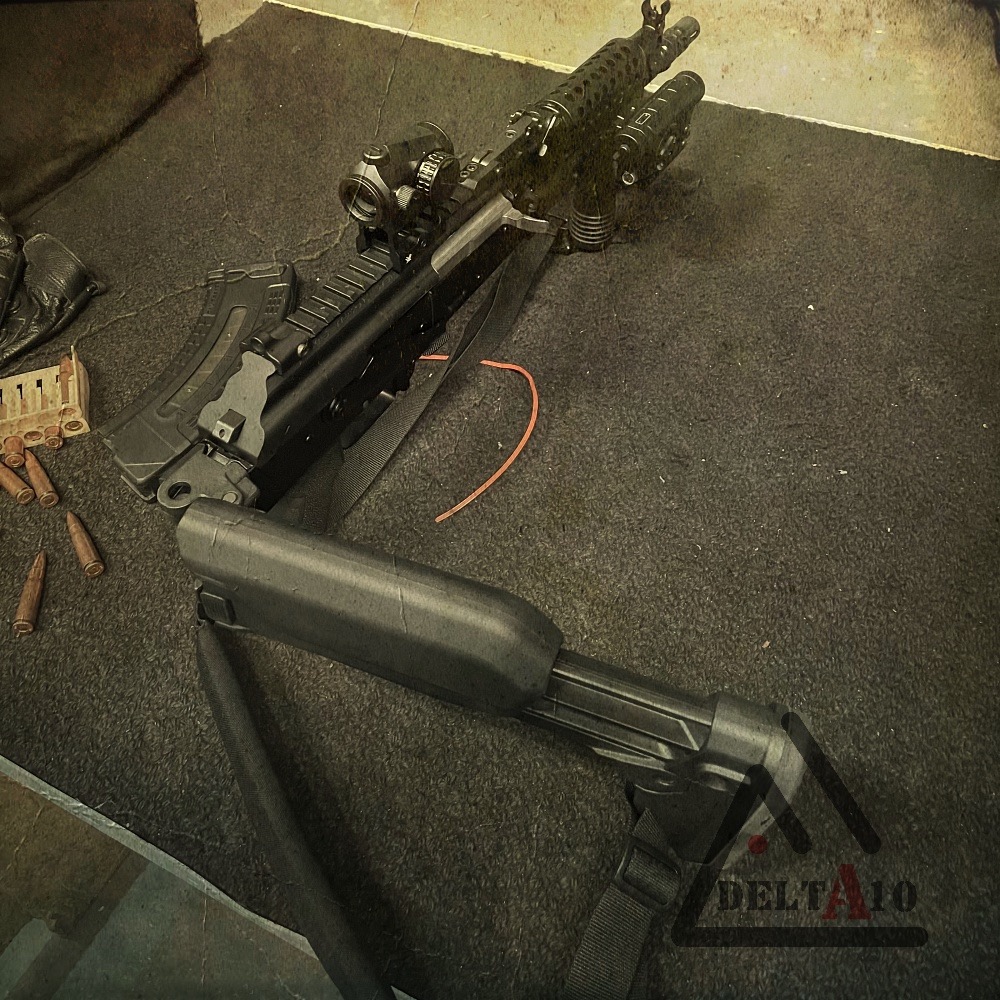 Czarny karabin z celownikiem optycznym i magazynkiem leżący na ciemnej, teksturowanej powierzchni, obok amunicji i skórzanych rękawic.