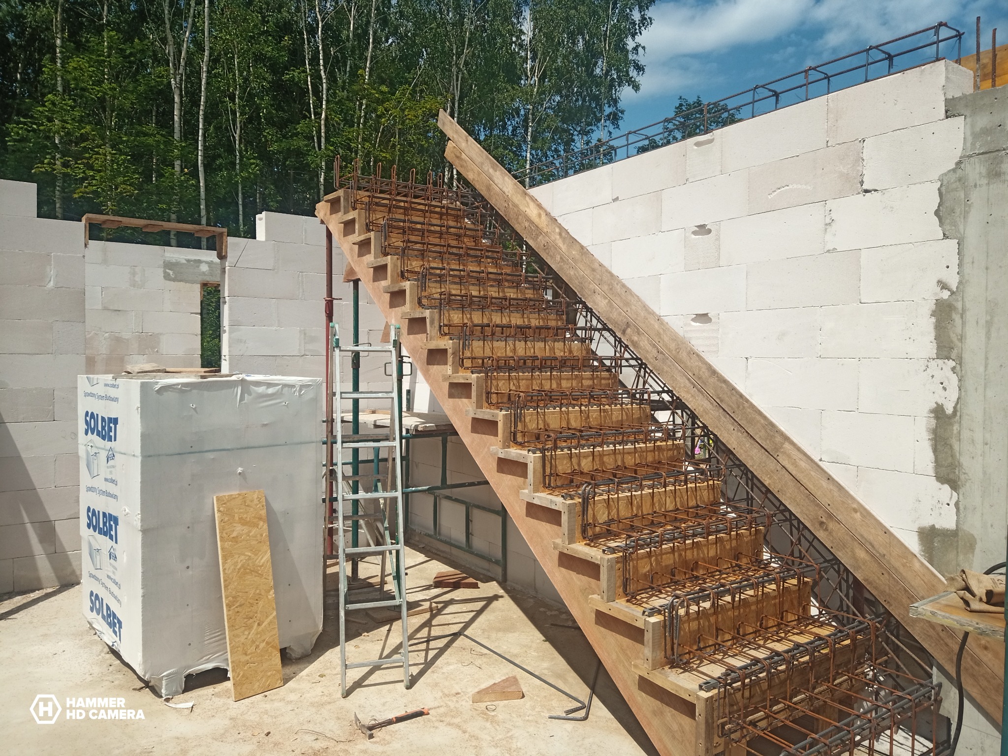 Konstrukcja schodów żelbetowych w trakcie budowy domu z bloczków Solbet, widoczna drabina i elementy szalunku.
