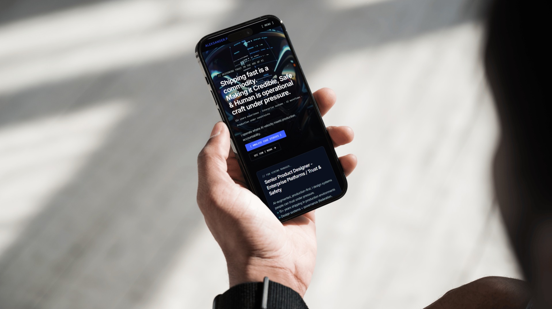 Osoba trzyma smartfon z widoczną stroną internetową prezentującą projekt interfejsu użytkownika z tekstem o budowaniu zaufania i bezpieczeństwa w systemach AI.