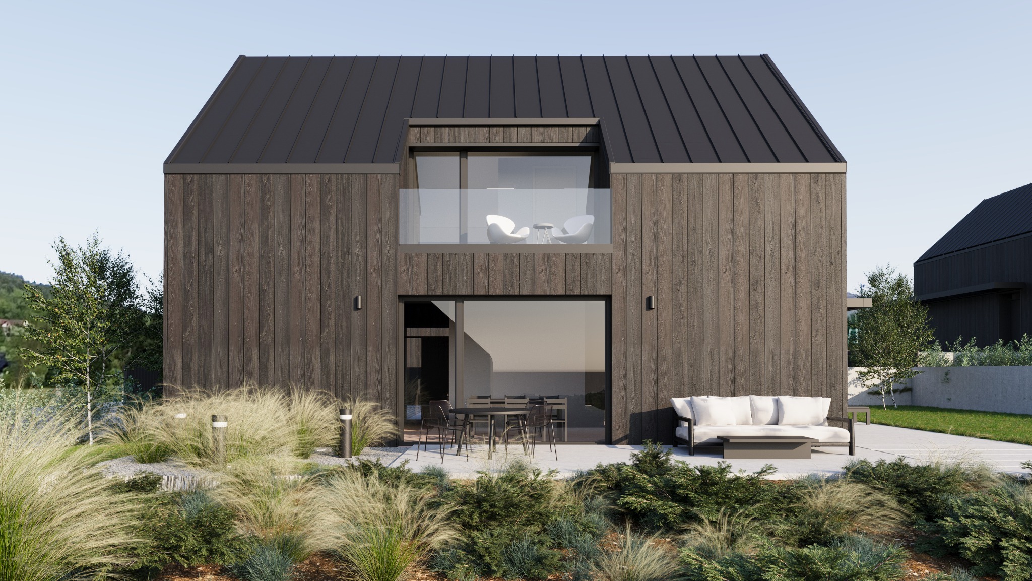 Nowoczesny dom z ciemnego drewna z balkonem z białymi krzesłami, tarasem z meblami ogrodowymi i ozdobnymi trawami na pierwszym planie.