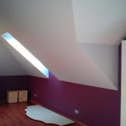 Poddasze po malowaniu: fioletowa ściana, biały sufit ze skośnym oknem, drewniana podłoga. Widoczne meble i fragment płyty. Detal wykończenia wnętrza.