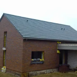 Nowy dach z szarej dachówki ceramicznej na domu z cegły klinkierowej w Świętochłowicach. Widoczne detale wykończenia i elementy konstrukcyjne.