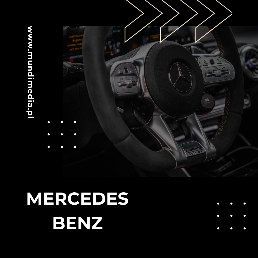 Szczegółowe ujęcie kierownicy Mercedes-Benz AMG Edition z widocznym logo marki i elementami sterowania, w tle deska rozdzielcza z wyświetlaczem.