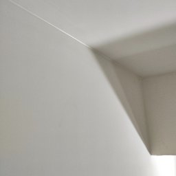 Bart-Dom - Biała ściana i sufit połączone pod kątem prostym, widoczna delikatna linia łączenia, oświetlona z prawej strony, tworząca cień na suficie.