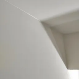 Biała ściana i sufit połączone pod kątem prostym, widoczna delikatna linia łączenia, oświetlona z prawej strony, tworząca cień na suficie.