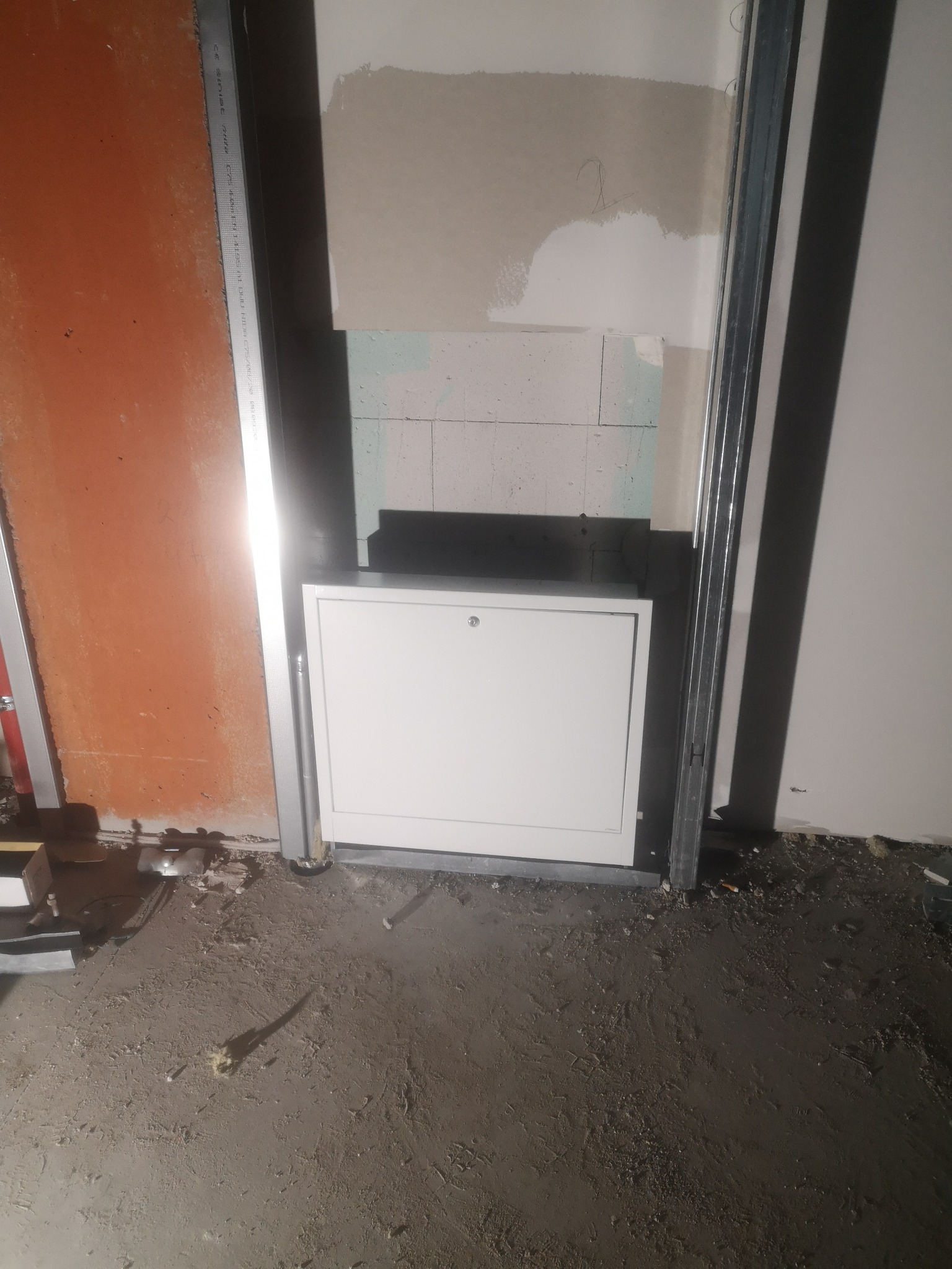 Biała skrzynka rewizyjna zabudowana w ścianie w Gdyni, widoczna w trakcie prac wykończeniowych z elementami metalowej konstrukcji i surowego podłoża.