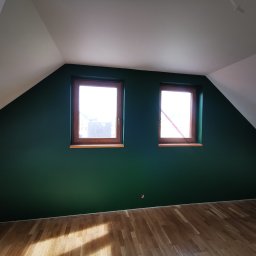 Mura-Dom - Poddasze po remoncie: ściana pomalowana na ciemnozielony kolor, drewniane okna i parkiet, białe skosy sufitu.