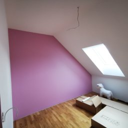 Mura-Dom - Pomalowane na różowo poddasze ze skosami i oknem dachowym, na podłodze panele i kilka kartonów, w rogu pokoju pluszowy jednorożec.