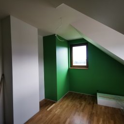 Mura-Dom - Poddasze po remoncie: zielone ściany, drewniane okno, białe skosy, parkiet i styropian, widoczne kable zwisające z sufitu.