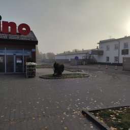 Biuro Rachunkowe Maja Dziuk - Fasada sklepu spożywczego Dino w jesienny, mglisty poranek, z widocznymi w oddali budynkami usługowymi i parkingiem usłanym liśćmi.