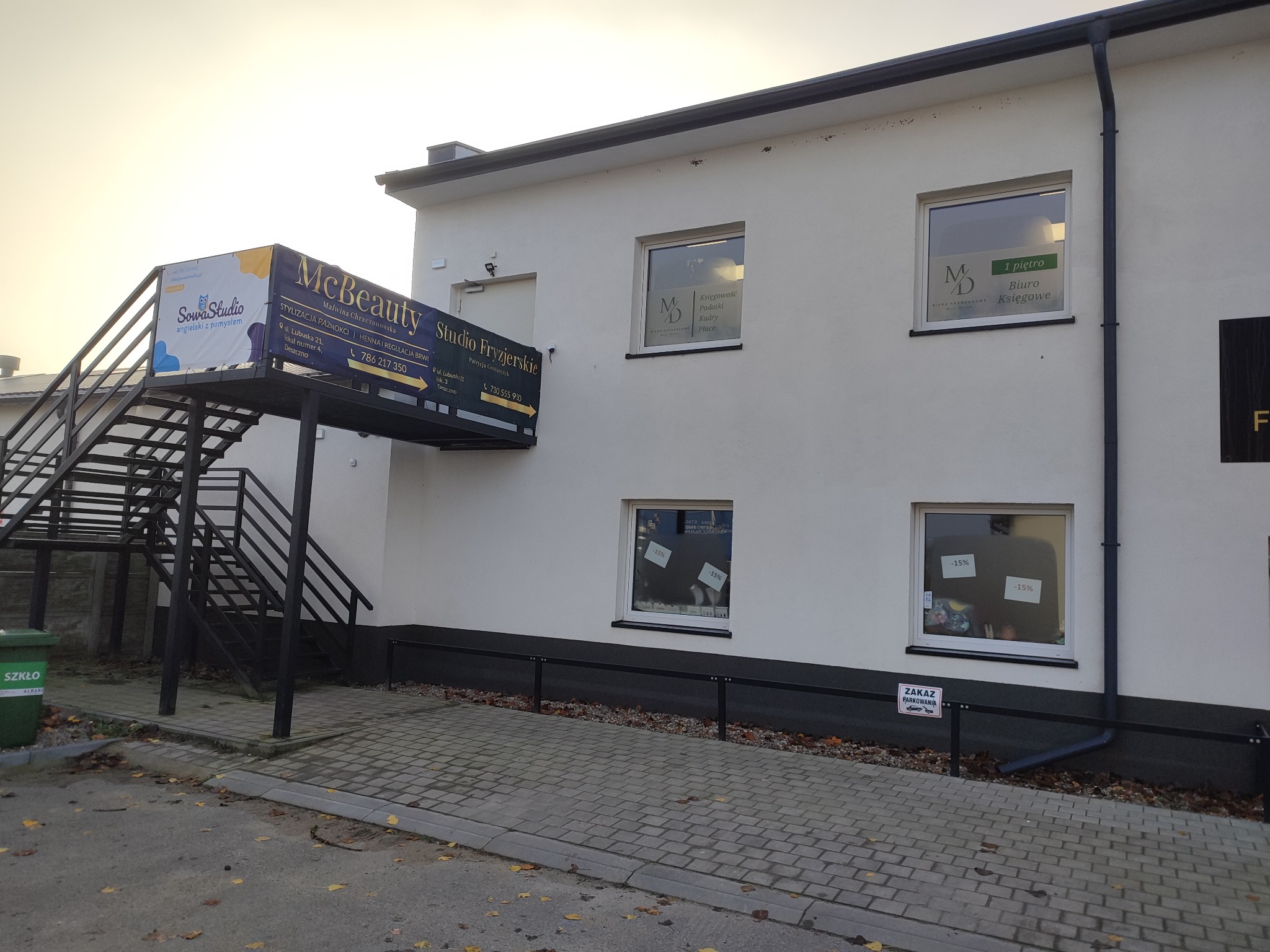 Elewacja budynku z reklamami firm McBeauty Studio Fryzjerskie, Sowa Studio oraz szyldem informującym o biurze księgowym na pierwszym piętrze, z informacją o ofercie kadrowo-płacowej.