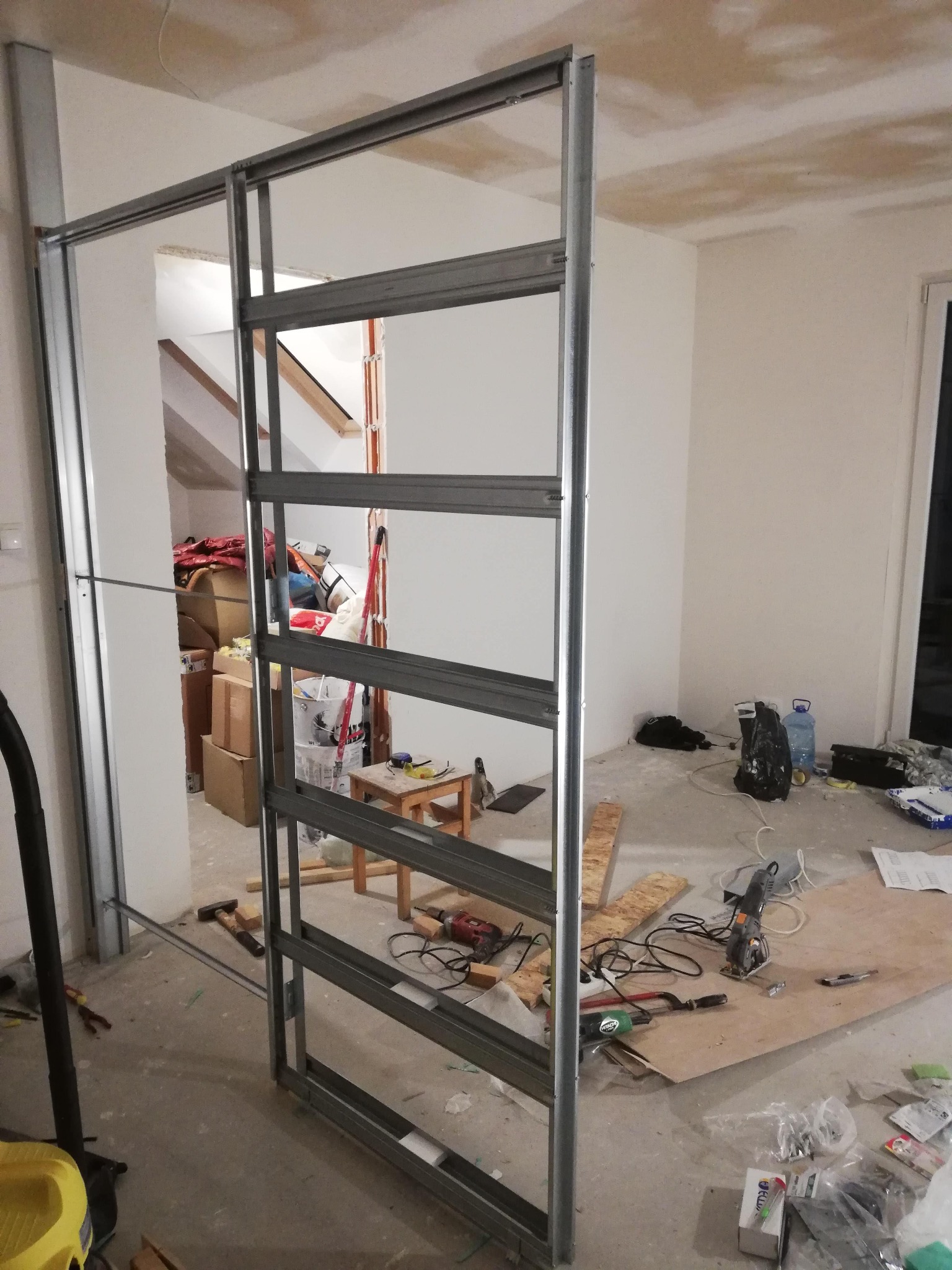 Montaż metalowej konstrukcji ścianki działowej w trakcie remontu w Krakowie, widoczne narzędzia i materiały budowlane, surowy stan wykończenia wnętrza.