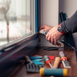 ODNOWA OKNA SPÓŁKA Z OGRANICZONĄ ODPOWIEDZIALNOŚCIĄ - Montażysta przycina uszczelkę w oknie, widoczne narzędzia i zegarek na ręce, wnętrze z oknem w tle.