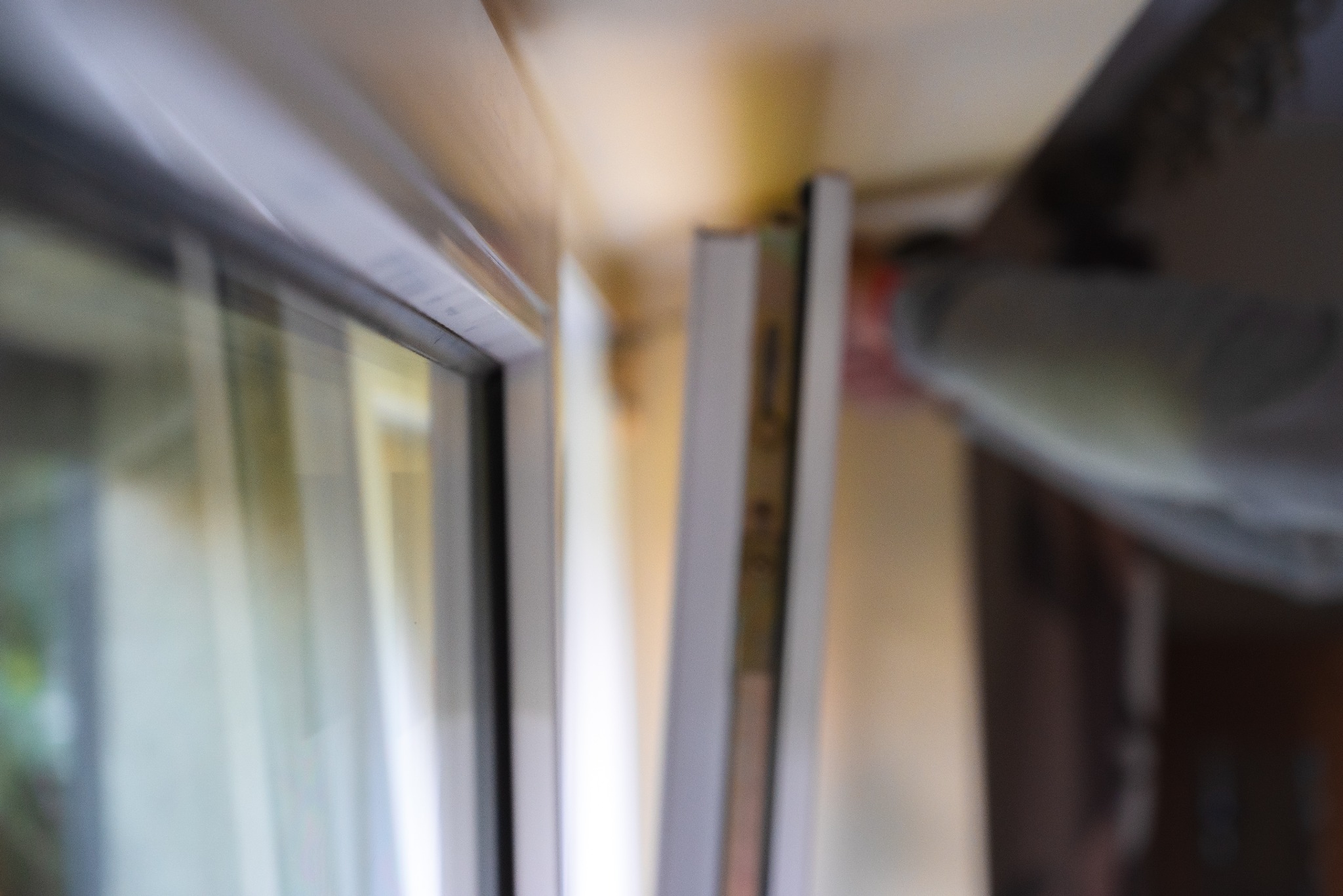 Niejasne ujęcie z bliska ramy okiennej podczas montażu, widoczna ręka montażysty w tle.