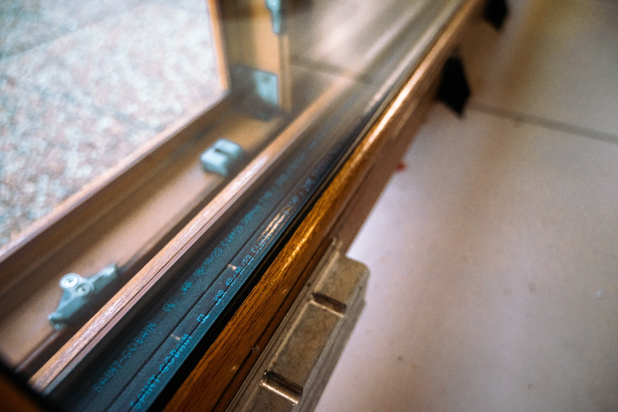 Przekrój okna z widocznymi uszczelkami firmy Saint-Gobain oraz elementami okuć, ukazujący detale konstrukcyjne.