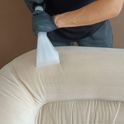 Brilliant Clean Paulina Jaworska - Pranie jasnej, pluszowej kanapy za pomocą ekstraktora; widoczna dysza i logo firmy Brilliant Clean na koszulce pracownika.