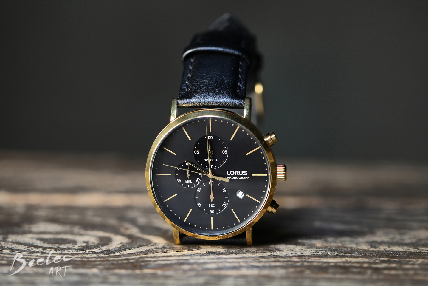 Zdjęcie produktowe zegarka Lorus Chronograph z czarną tarczą i złotą kopertą na drewnianym tle, wykonane przez Bielec Art.