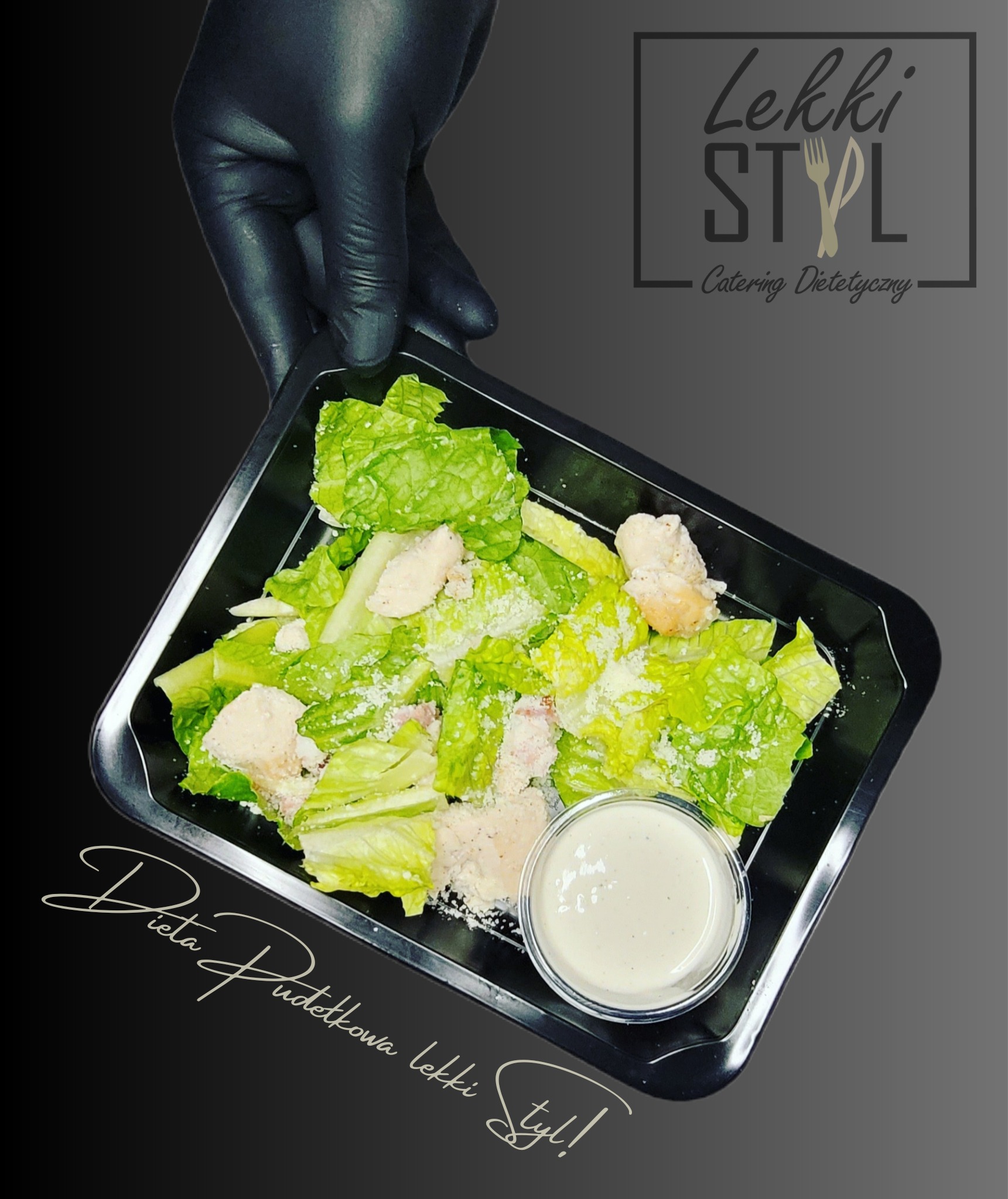 Sałatka Cezar z kurczakiem w czarnym pojemniku, trzymana w dłoni w czarnej rękawiczce, obok logo firmy cateringowej i napisu 'Dieta Pudełkowa Lekki Styl!'