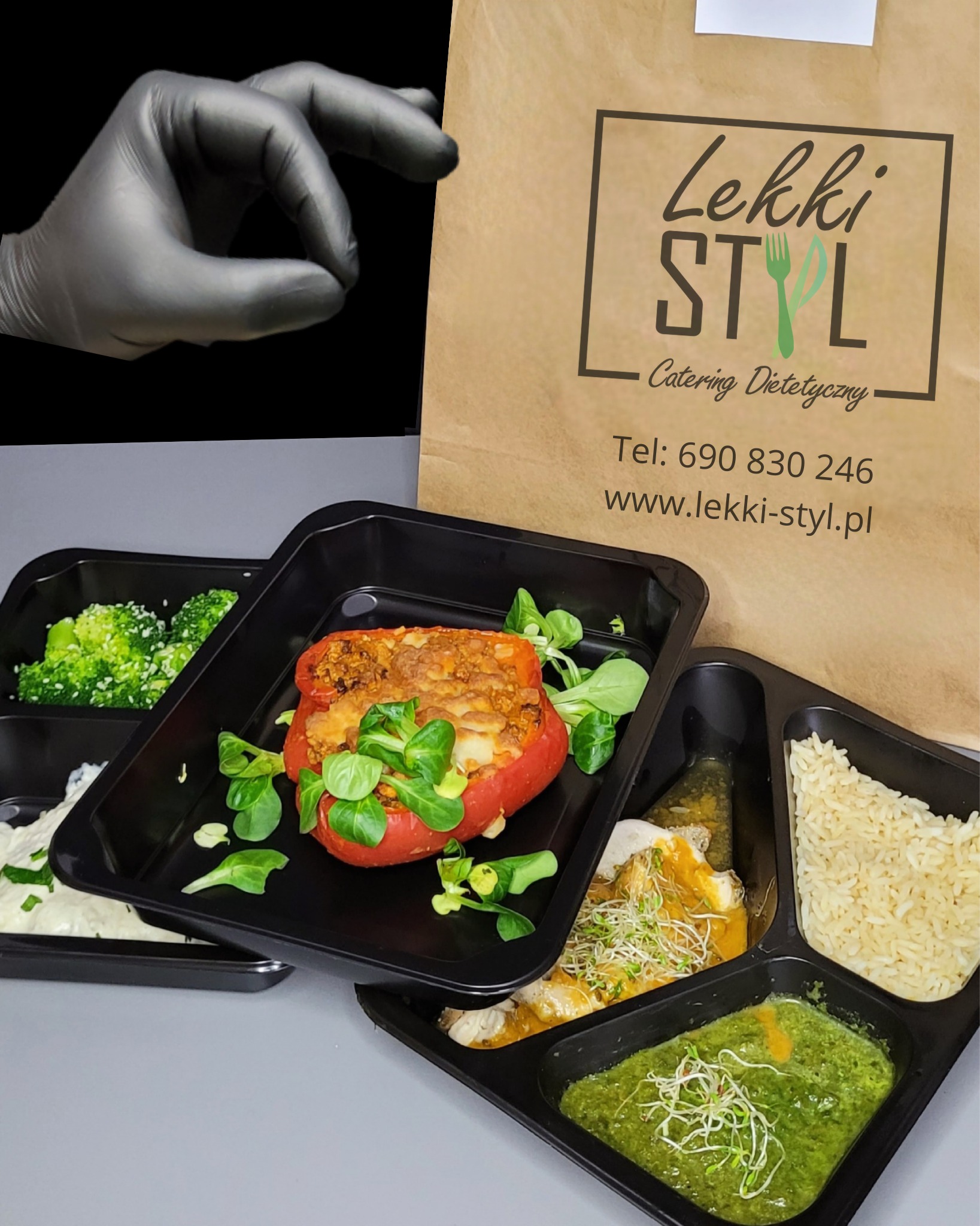Zestaw posiłków w czarnych pojemnikach: faszerowana papryka, brokuły z sezamem, sos śmietanowy, kurczak w sosie, zielone pesto, ryż, oraz dłoń w czarnej rękawiczce i torba z logo firmy.