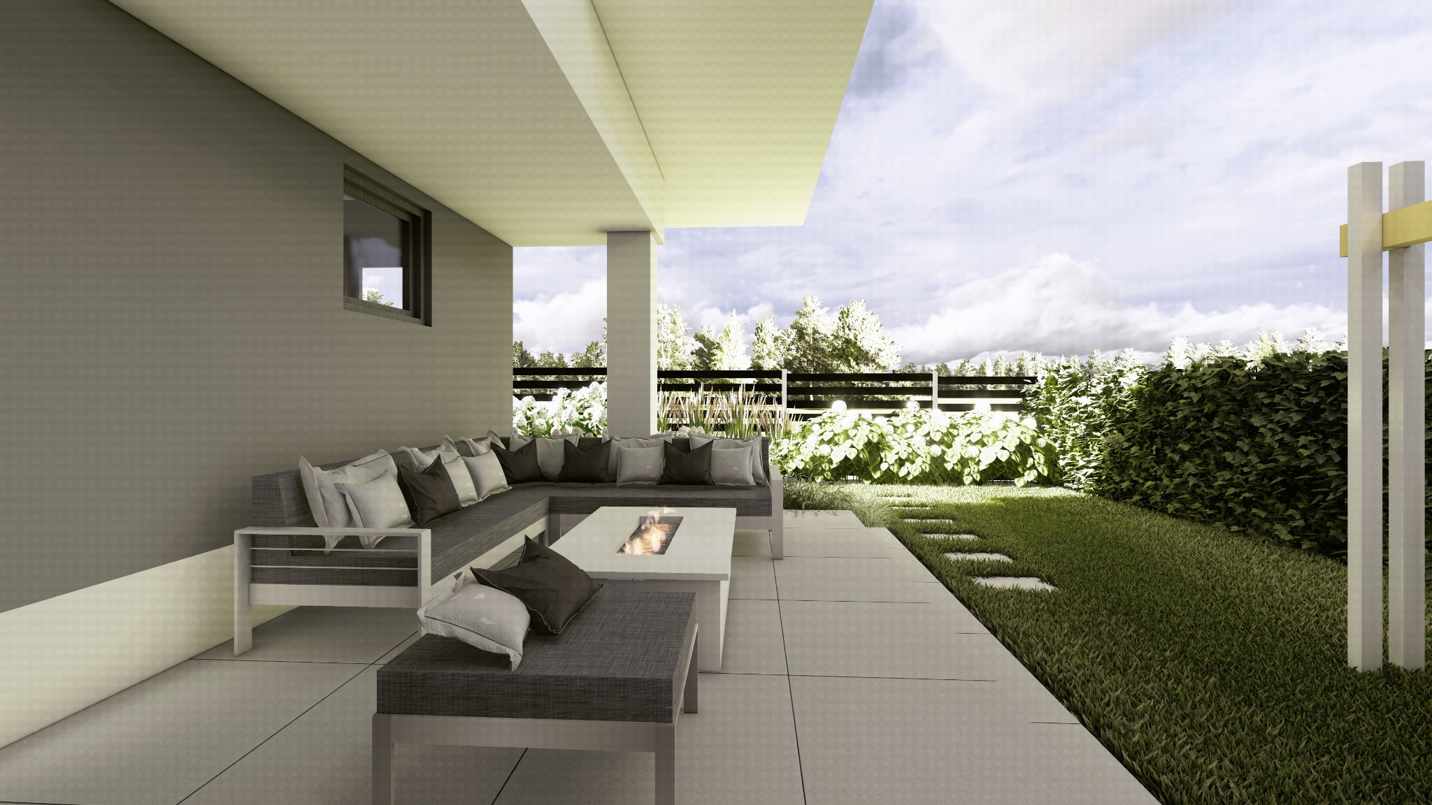 Zadaszony taras z szarą sofą narożną, poduszkami i stolikiem z paleniskiem, widok na ogród z żywopłotem i ścieżką z płyt.