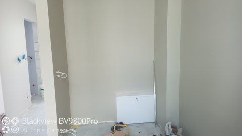 Świeżo pomalowane wnętrze z widoczną skrzynką elektryczną i wystającymi przewodami, przygotowane do dalszych prac wykończeniowych.