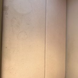 Piorex - Pranie tapicerki meblowej i samochodowej - Fragment jasnoróżowej kanapy z widocznymi plamami i zabrudzeniami, ujęcie z góry.