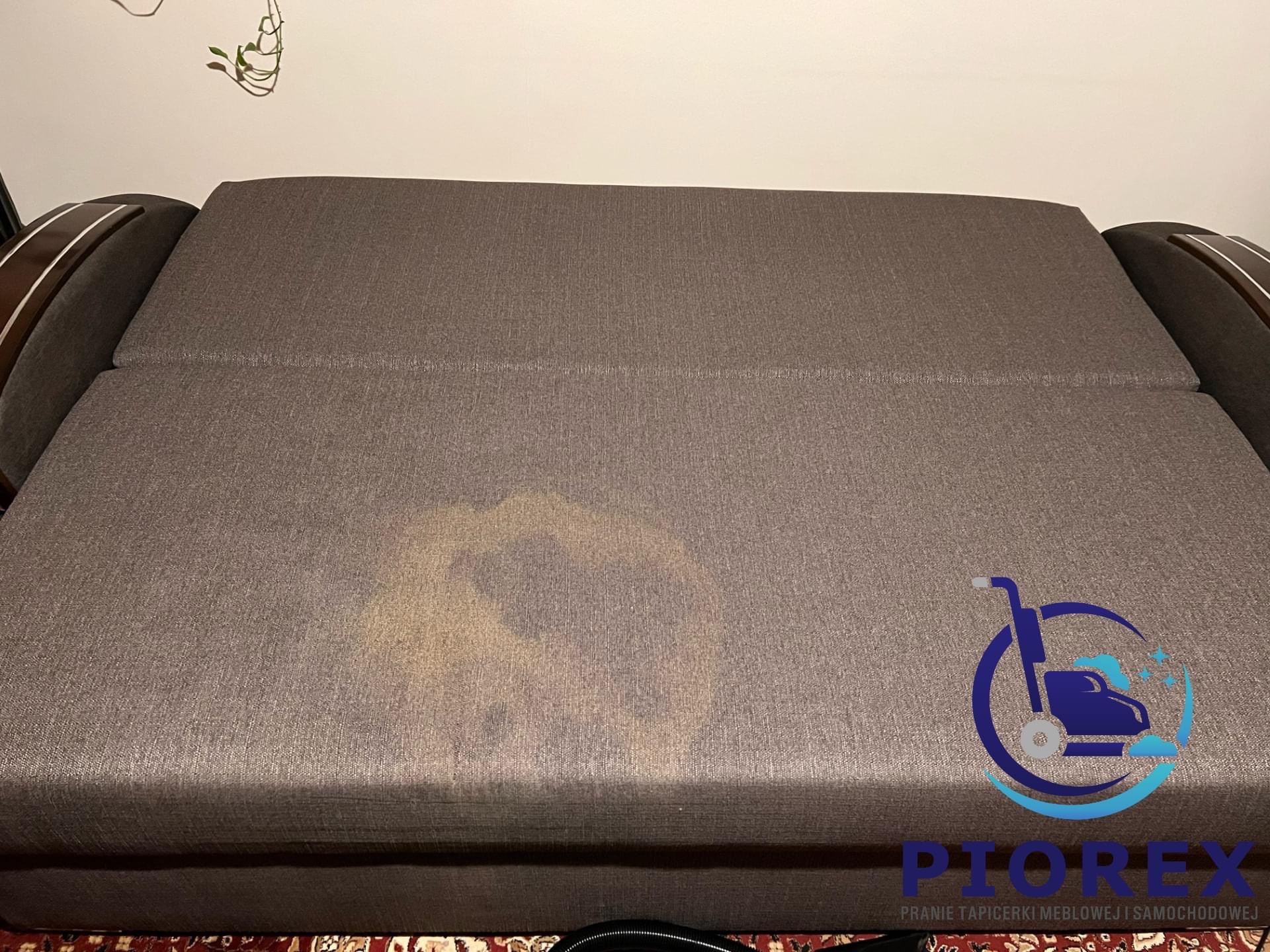 Brązowa rozkładana sofa z widocznym, jasnym przebarwieniem na siedzisku, sugerującym plamę przed czyszczeniem.