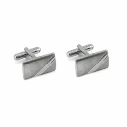 Para srebrnych, prostokątnych spinek do mankietów z ukośnym wzorem na białym tle.