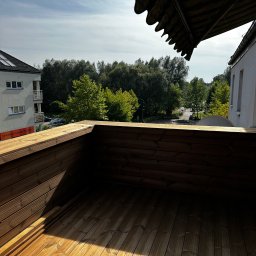 MC Design Jakub Ciuńczyk - Drewniany taras z widokiem na zieleń miejską, cień markizy na deski, w tle budynek mieszkalny.