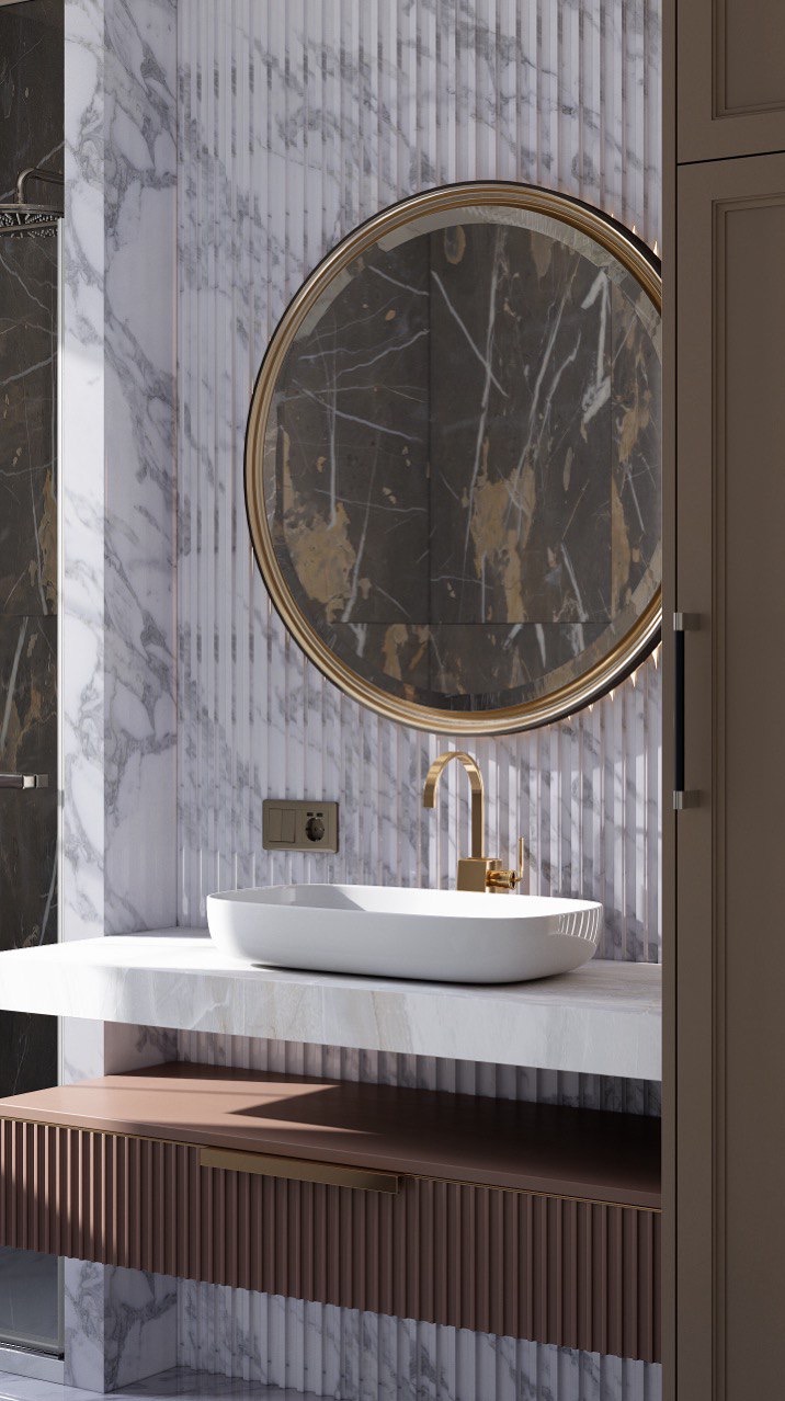 Elegancka łazienka z umywalką nablatową, złotą armaturą i okrągłym lustrem w złotej ramie. Ściany wykończone marmurem i panelami dekoracyjnymi.