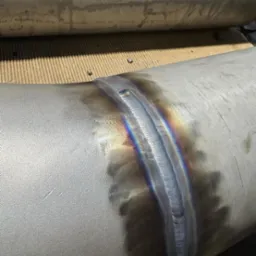 Spoina na rurze ze stali nierdzewnej z widocznymi kolorami hartowania, wykonana metodą TIG.