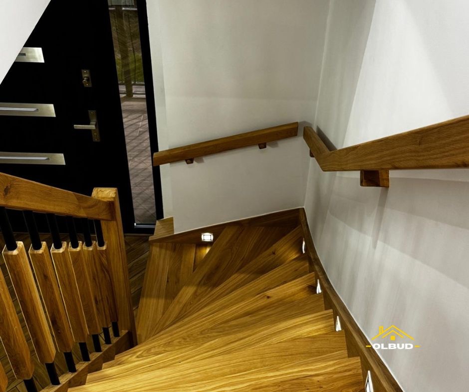 Drewniane schody kręcone z oświetleniem LED wzdłuż stopni i balustrad. Widok z góry, nowoczesne wykończenie, czarne elementy, białe ściany.