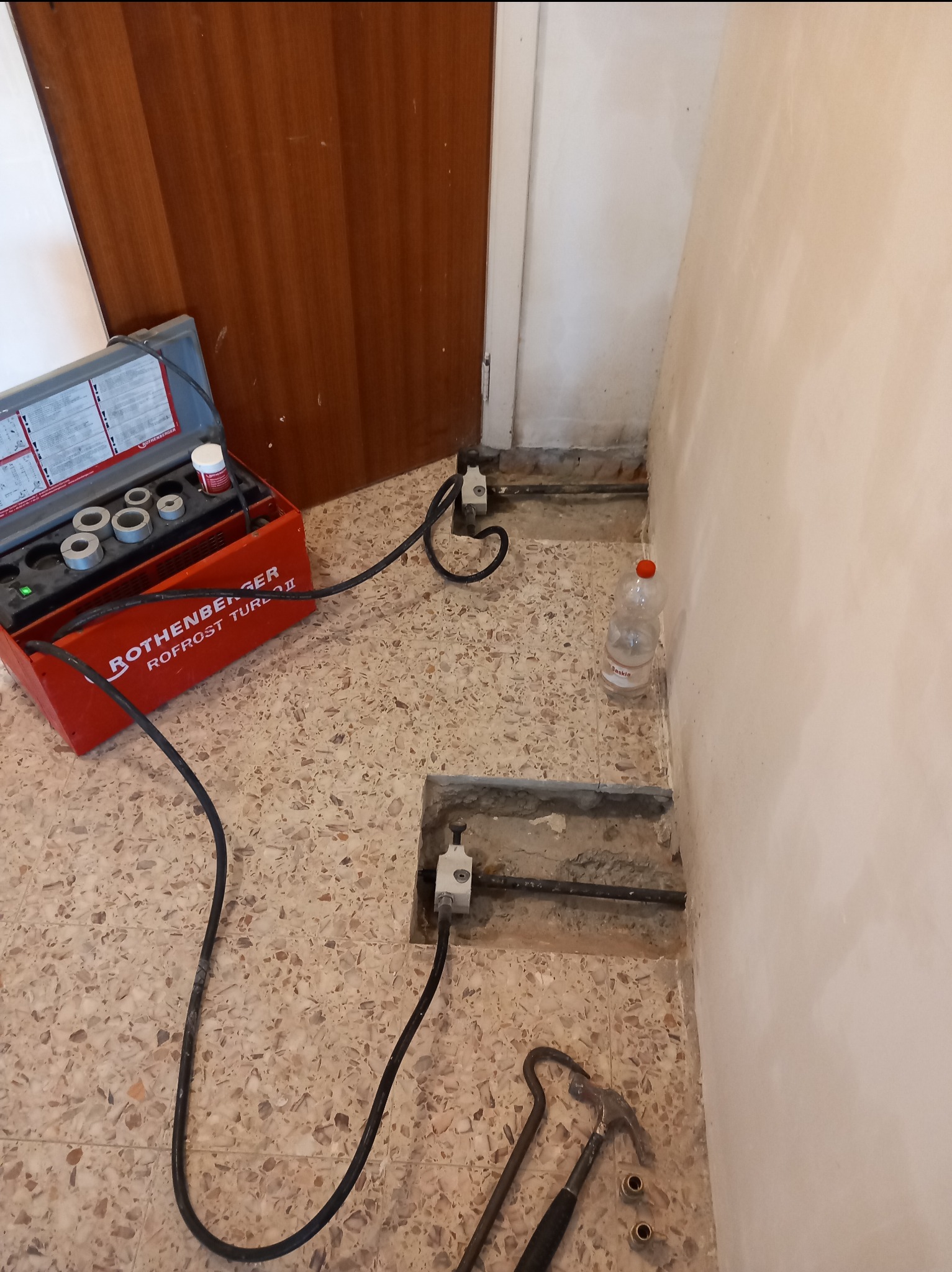 Zamrażanie rur miedzianych za pomocą urządzenia Rothenberger Rofrost Turbo II podczas prac remontowych w pomieszczeniu z terakotą.