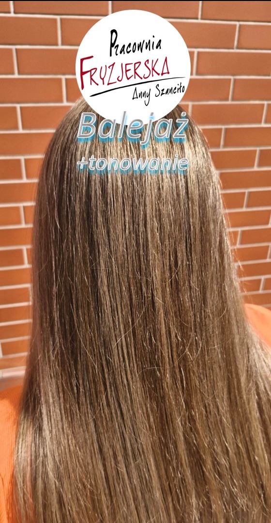 Włosy po balejażu i tonowaniu, widok z tyłu na tle ceglanej ściany. Nałożony filtr z nazwą salonu.