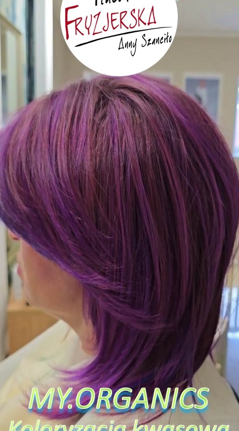 Fioletowe włosy po koloryzacji kwasowej My.Organics, widoczne z profilu, z logo salonu fryzjerskiego w górnej części kadru. Krótkie, warstwowe cięcie.