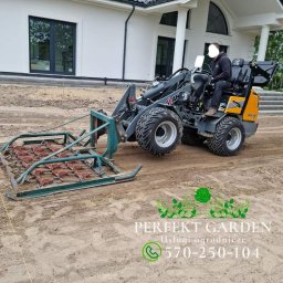 Perfekt Garden Usługi Ogrodnicze - Kompaktowa ładowarka Giant G1200 HD z broną wahadłową wyrównuje teren pod przyszły trawnik przed nowoczesnym domem z białymi kolumnami.