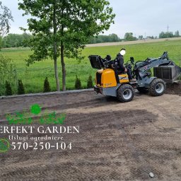 Perfekt Garden Usługi Ogrodnicze - Żółto-szara mini ładowarka marki Giant w trakcie wyrównywania terenu pod przyszły ogród, obok pracownik z łopatą, w tle zielone pole i drzewa.