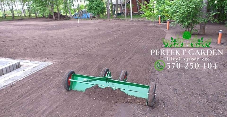 Przygotowanie terenu pod trawnik: wyrównywanie gleby za pomocą zielonego walca z czterema kołami, w tle widoczne drzewa i elementy małej architektury ogrodowej oraz logo firmy 'Perfekt Garden'.