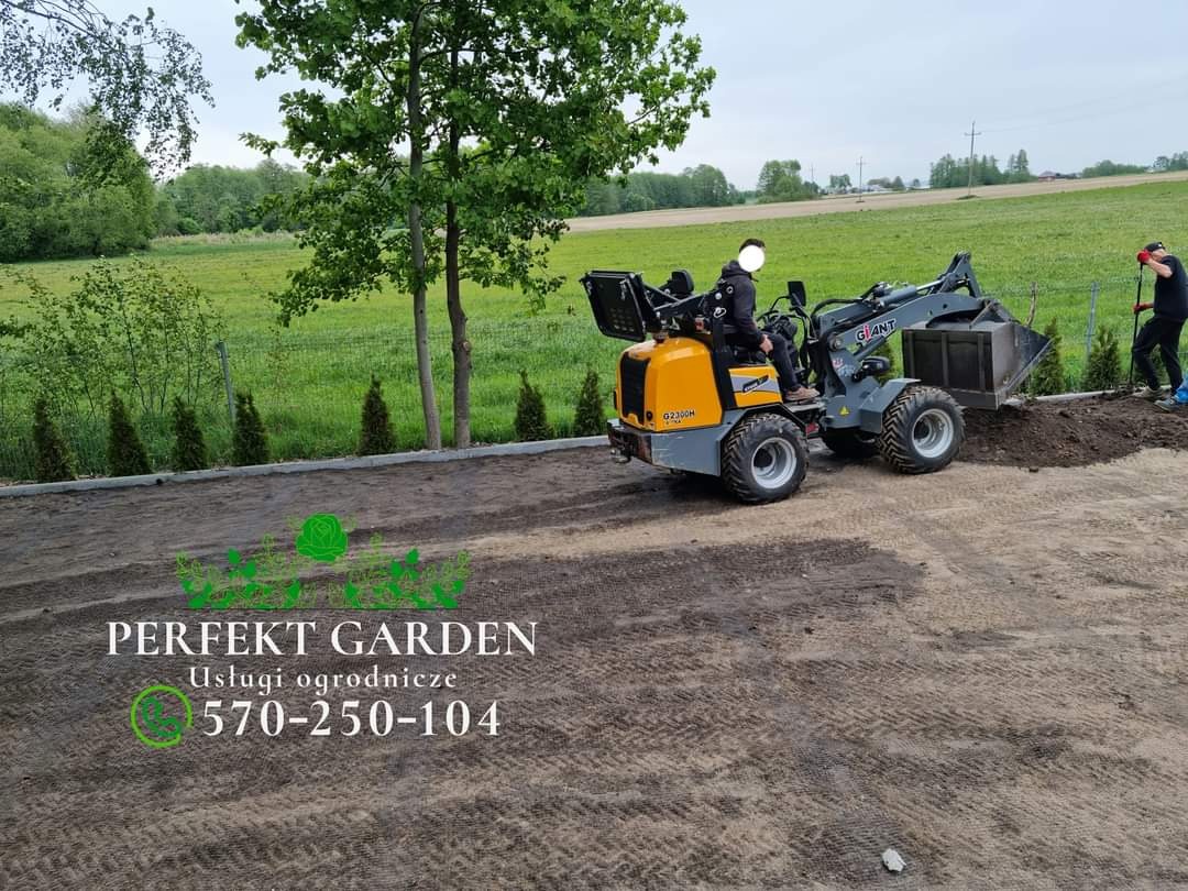 Żółto-szara mini ładowarka marki Giant w trakcie wyrównywania terenu pod przyszły ogród, obok pracownik z łopatą, w tle zielone pole i drzewa.