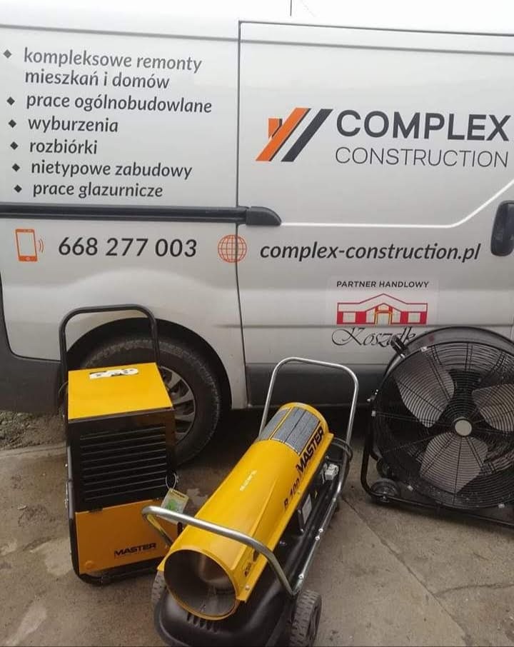 Żółte nagrzewnice Master B 100 i przenośny wentylator na tle firmowego busa z logo Complex Construction i numerem telefonu.