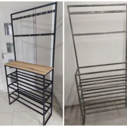 Metalowy regał na buty z wieszakami, po lewej stronie pomalowany na czarno, z drewnianym blatem, po prawej stronie surowy metal o szarym odcieniu, konstrukcja spawana.
