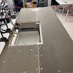 JOBI_BUD - Montaż płyty budowlanej na stelażu meblowym z wycięciem na szufladę, widoczne śruby mocujące, klemy stolarskie i narzędzia w tle.